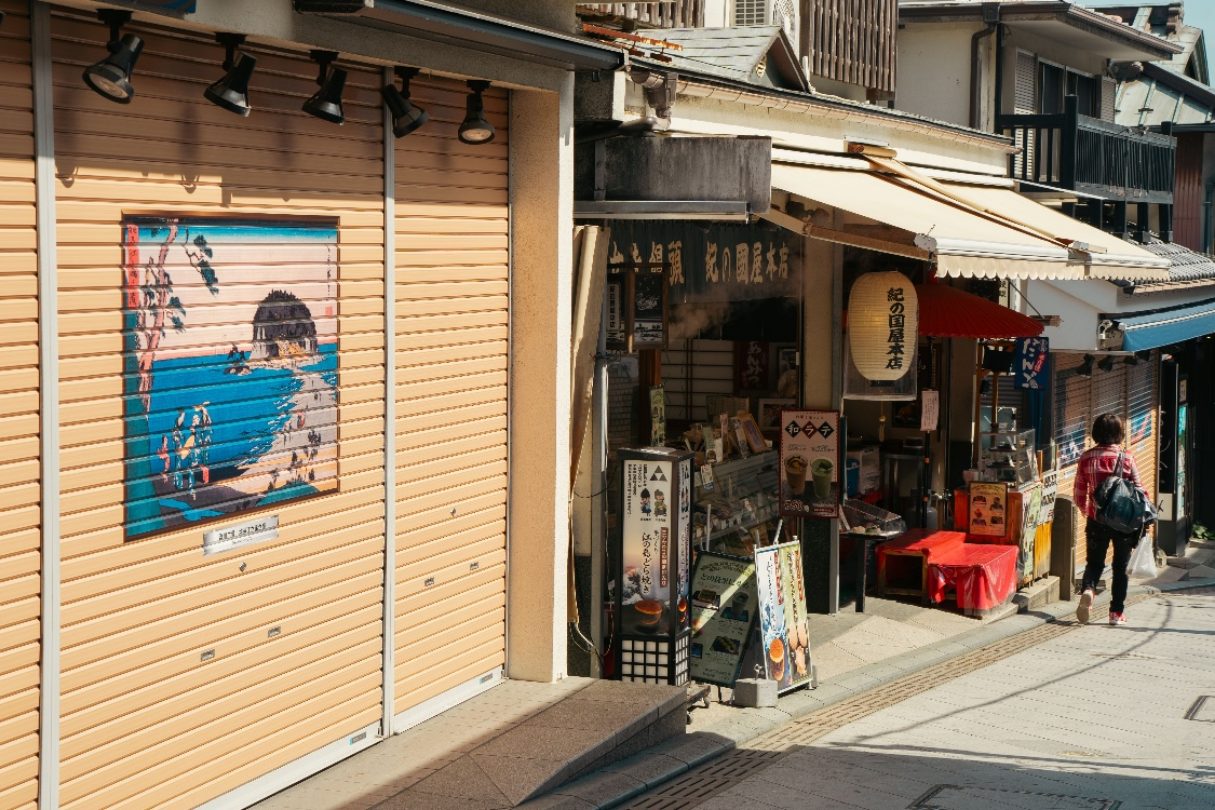 A small shopfront in daylight, its awning out and goods set along the pavement